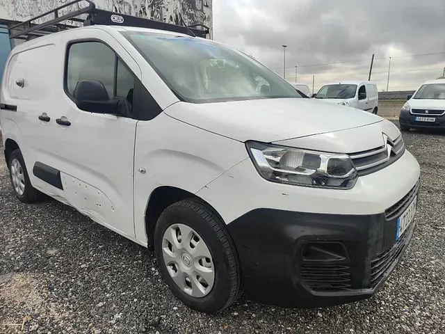 Una camioneta blanca está estacionada en un estacionamiento de grava.