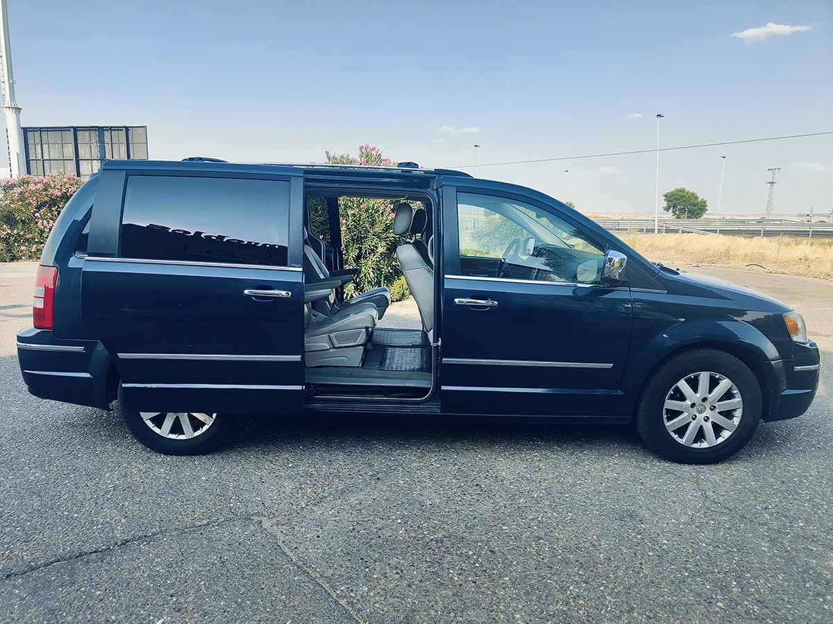 Minivan de color azul oscuro con la puerta lateral abierta, estacionada sobre asfalto.