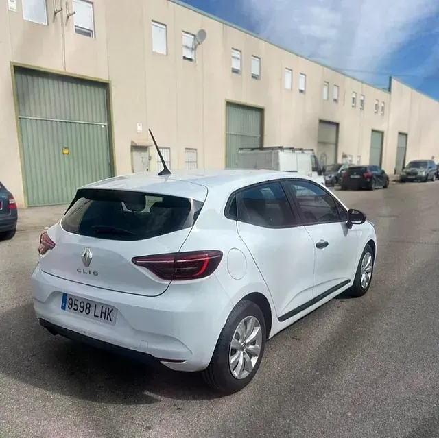 Un coche blanco está aparcado delante de un edificio.