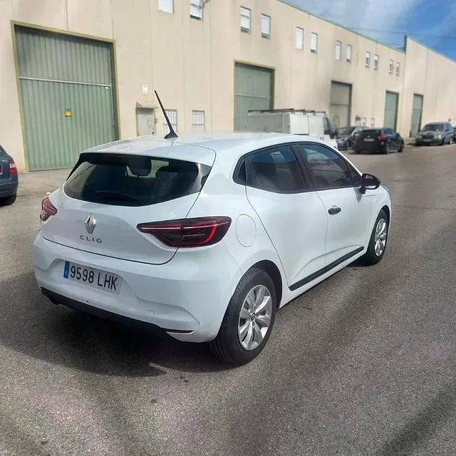 Un coche blanco está aparcado delante de un edificio.