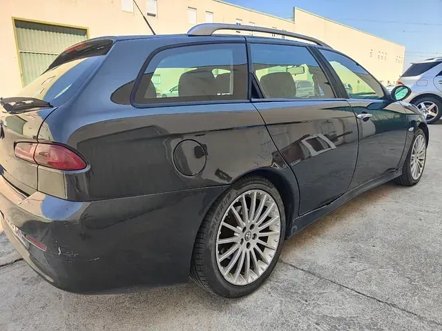 Un coche negro está aparcado en un estacionamiento frente a un edificio.