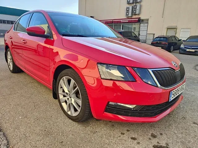 Un Skoda Octavia rojo está estacionado frente a un edificio.