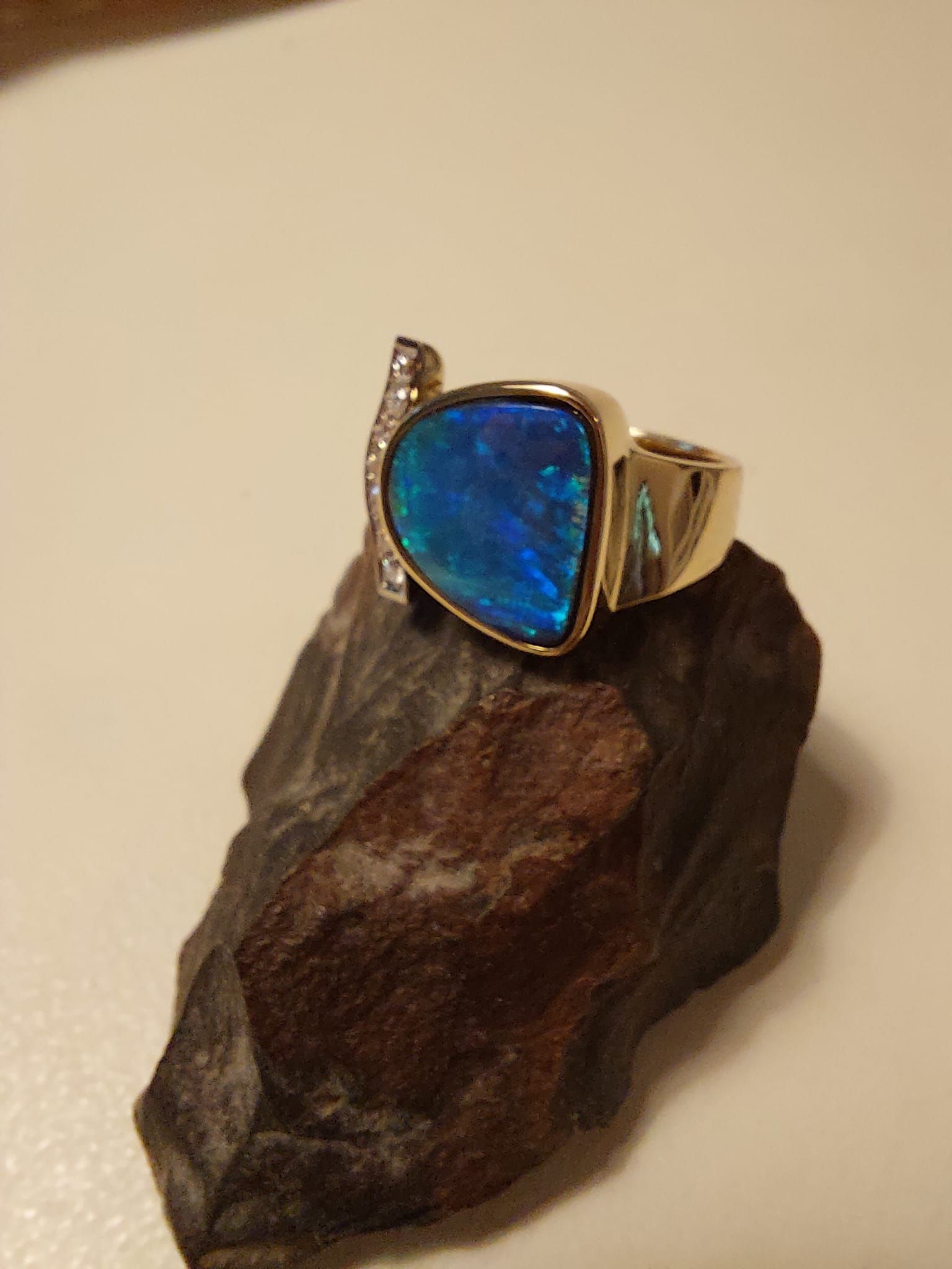 Goldring mit blauem Opal und Diamanten auf einem Stein.