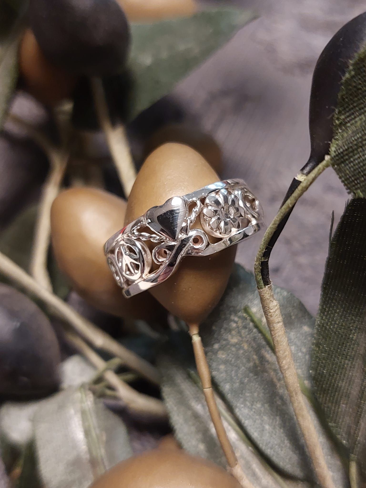 Silberner Filigranring auf Olivenzweig mit Oliven.