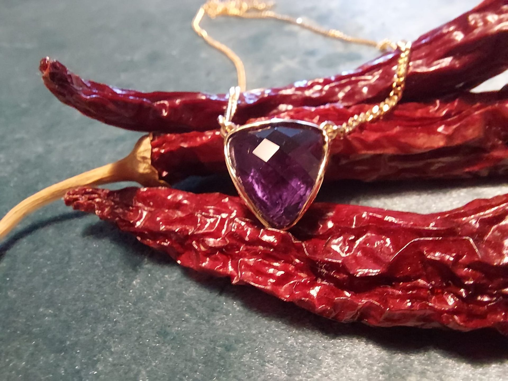 Halskette mit Anhänger aus violettem Edelstein und getrockneten roten Chilischoten.