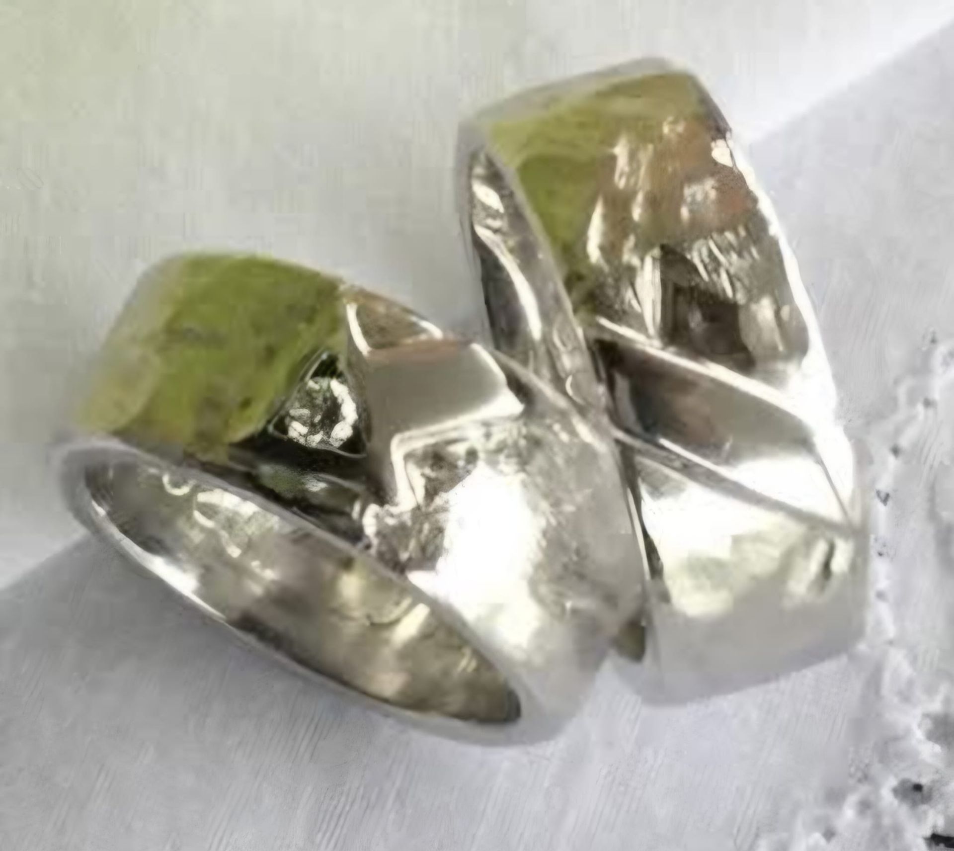 Zwei silberne Eheringe mit strukturierter Oberfläche, die auf weißer Spitze ruhen.