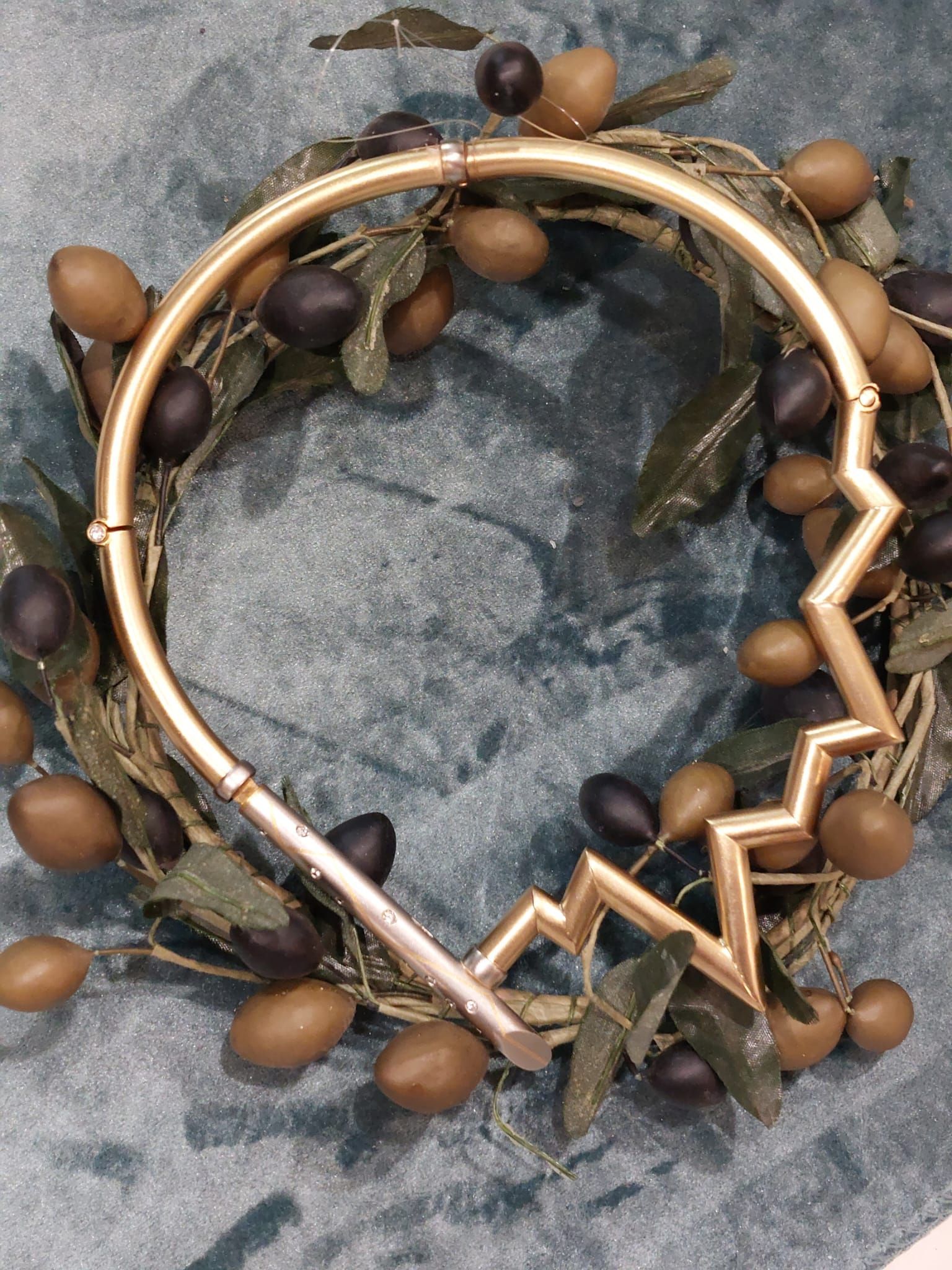 Goldene Halskette mit Zickzack-Design, eingefasst in einen Olivenkranz.