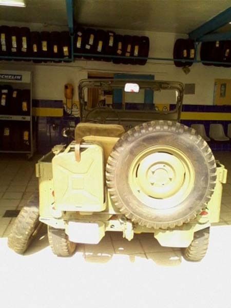 Un jeep está estacionado en un garaje con neumáticos en la pared.