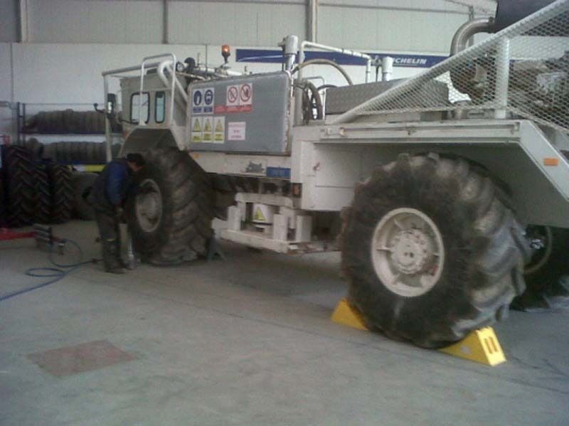 Un hombre está trabajando en un tractor grande en un garaje.