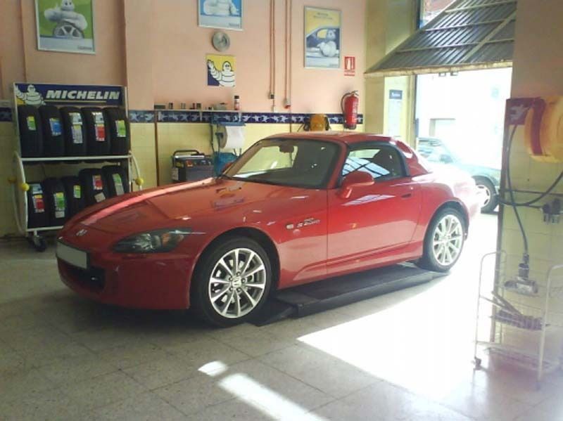 Un coche rojo está aparcado delante de un cartel Michelin.