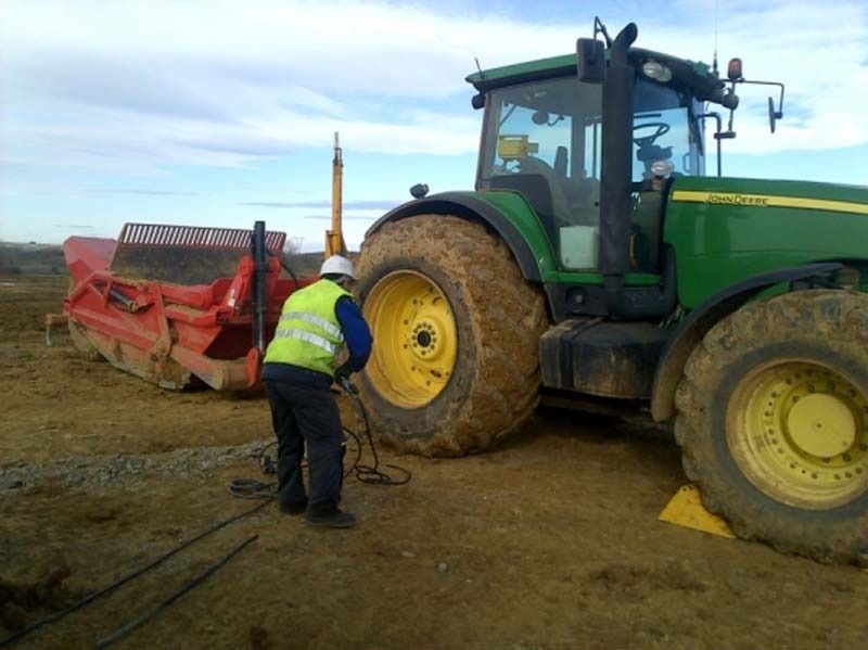 Un hombre está arreglando un neumático en un tractor John Deere.