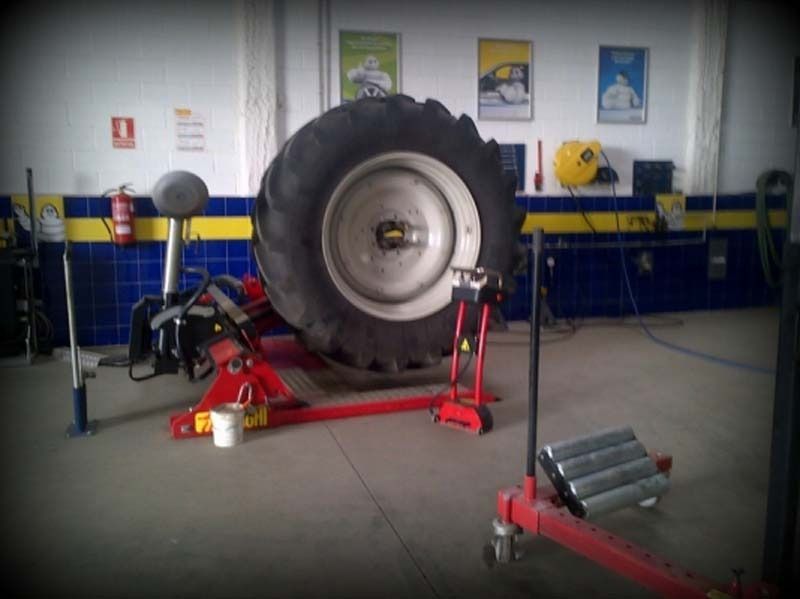 Un neumático de tractor está sobre un gato en un garaje.