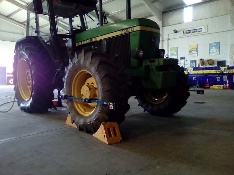 Un tractor John Deere verde está estacionado en un garaje.