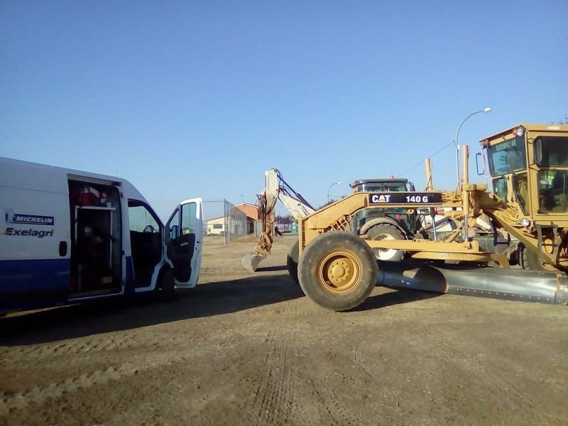 Una camioneta blanca está estacionada al lado de una excavadora.