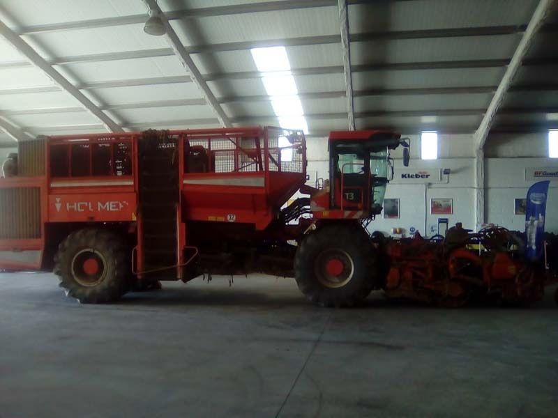 Un gran tractor rojo está estacionado en un almacén.