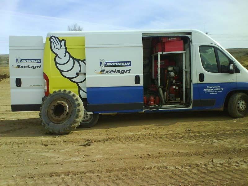 Una furgoneta Michelin está estacionada en un campo de tierra.