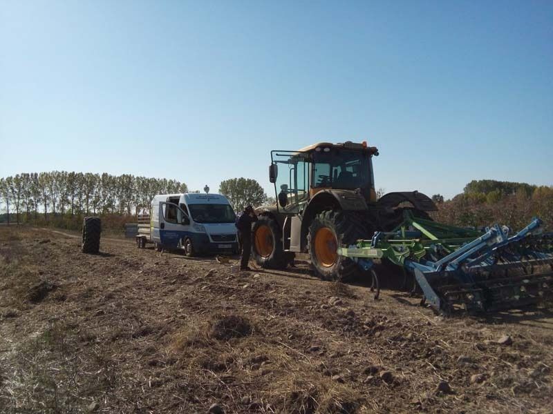 Un hombre está de pie junto a un tractor en un campo.