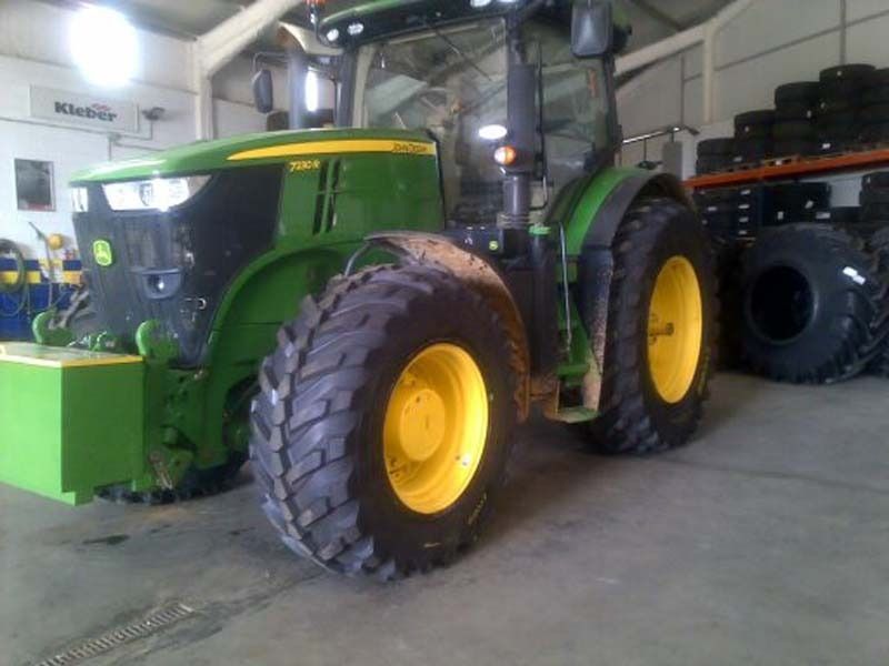 Un tractor John Deere verde y amarillo está estacionado en un garaje.