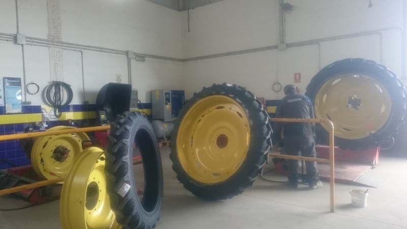 Un hombre está trabajando en un neumático de tractor en un garaje.