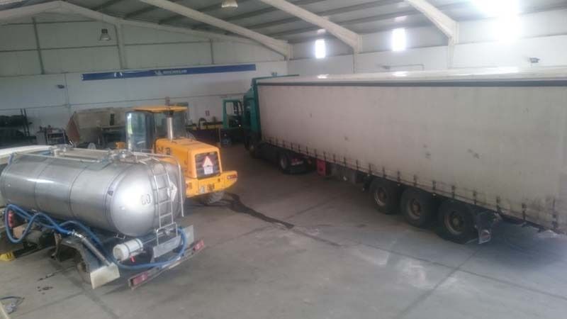 Un camión cisterna y un camión semirremolque están estacionados en un almacén.