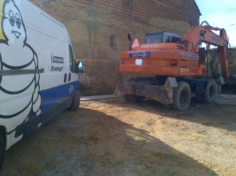Una furgoneta Michelin está aparcada junto a una excavadora.