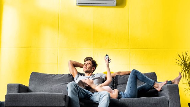Jeune couple profitant de la climatisation son leur canapé