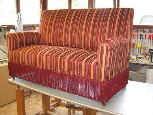 Eine Person arbeitet an dem Polster eines Stuhles mit einer Bohrmaschine.