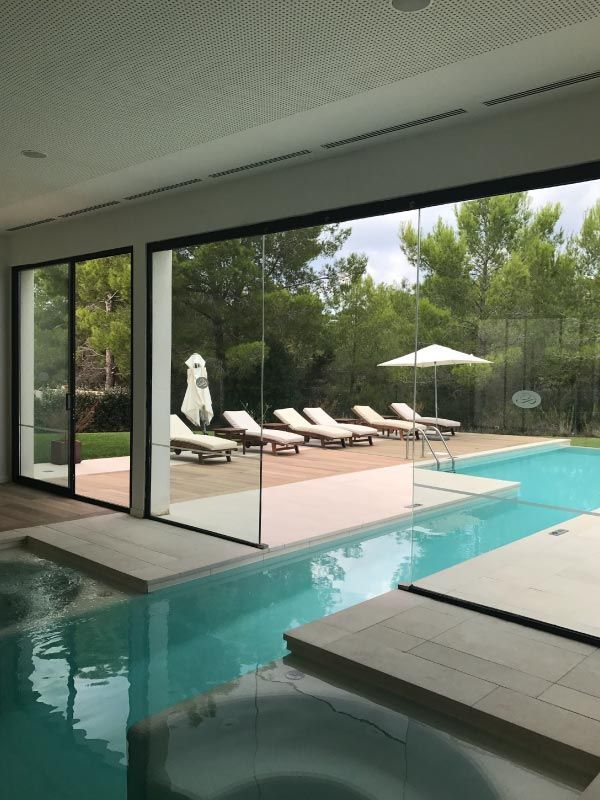 Una gran piscina cubierta con sillas y sombrillas al fondo.