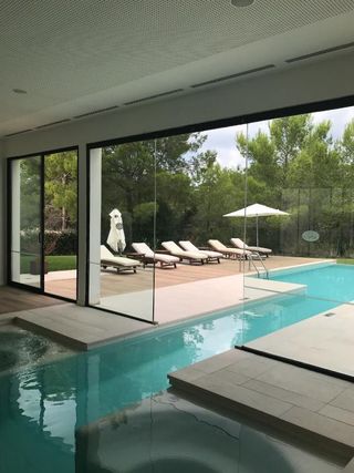 Una gran piscina cubierta con sillas y sombrillas al fondo.