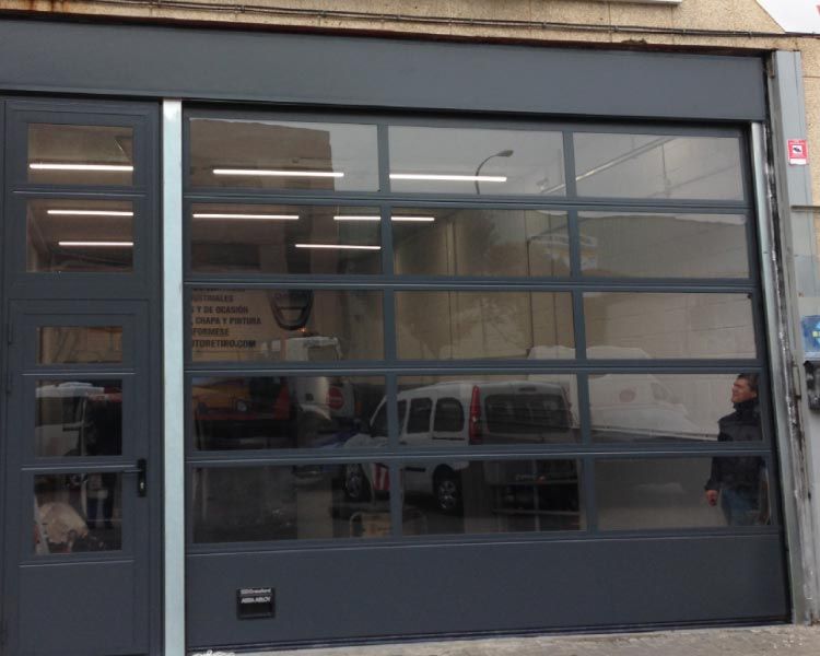 Un hombre está parado frente a una gran puerta de garaje.