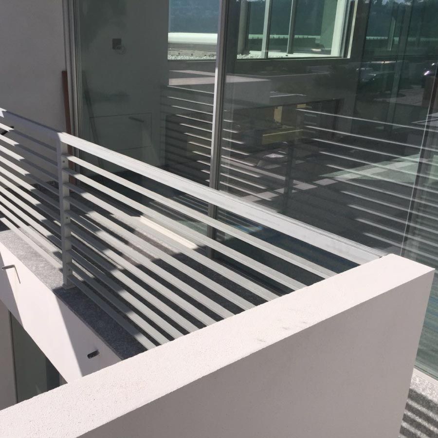 Un balcón con barandilla blanca y puerta de cristal.