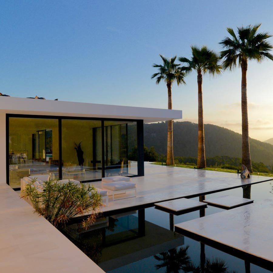 Una casa con piscina y palmeras delante de ella.