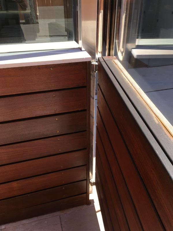 Una caja de madera se encuentra junto a una ventana en un balcón.