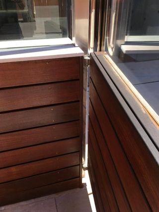 Una caja de madera se encuentra junto a una ventana en un balcón.