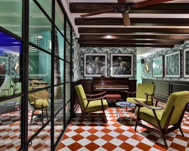 Una sala de estar con sillas verdes y un piano.