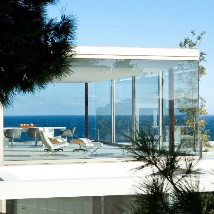 Una casa con muchas ventanas con vistas al océano.