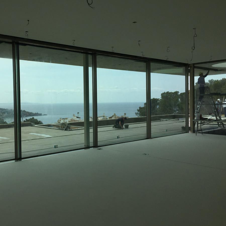 Un hombre parado en una escalera en una habitación vacía con vista al océano.