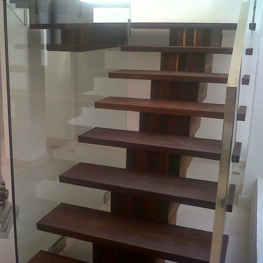 Una escalera con escalones de madera y barandilla de cristal.