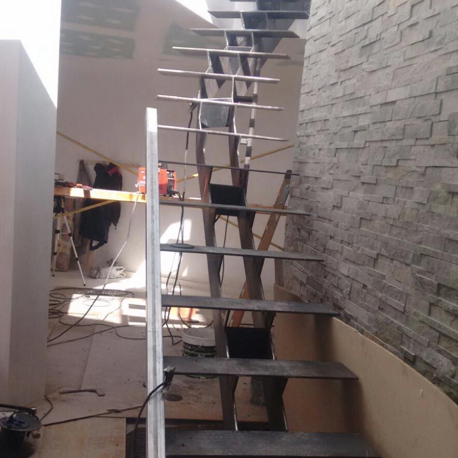 Una escalera de metal con una pared de ladrillos detrás.