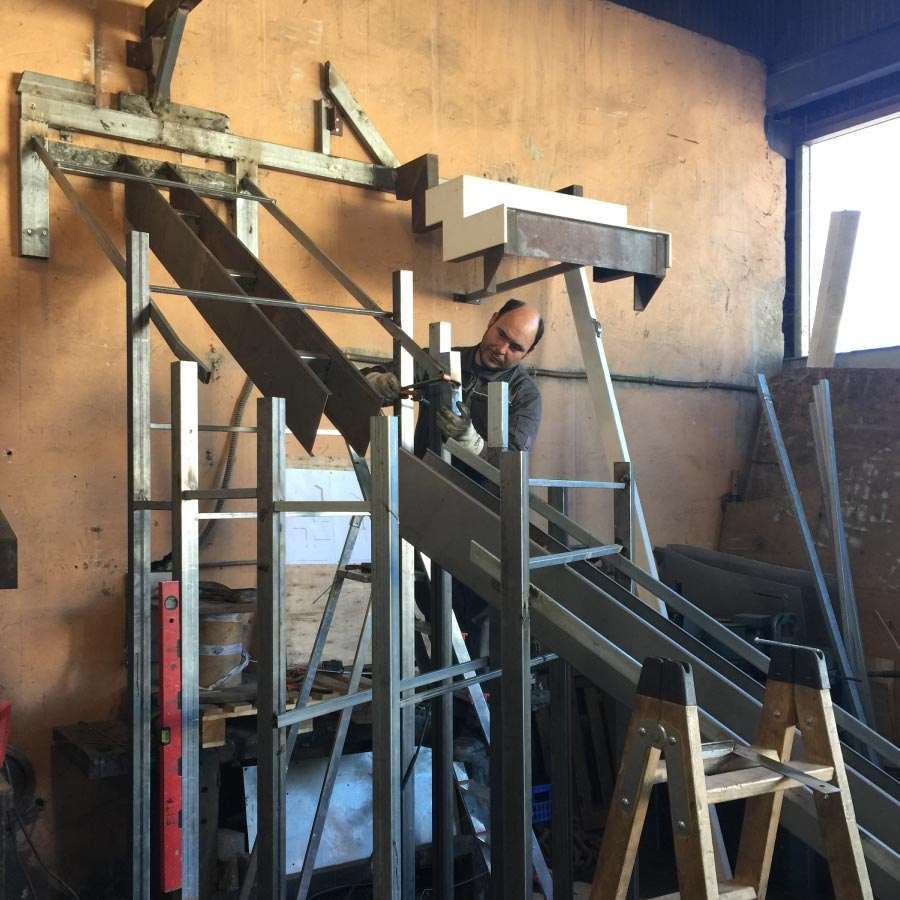 Un hombre está trabajando en un conjunto de escaleras de metal.