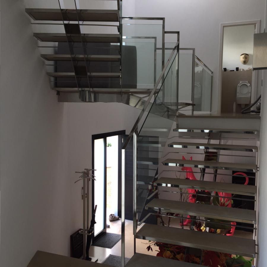 Una escalera con barandilla de vidrio que conduce al segundo piso.