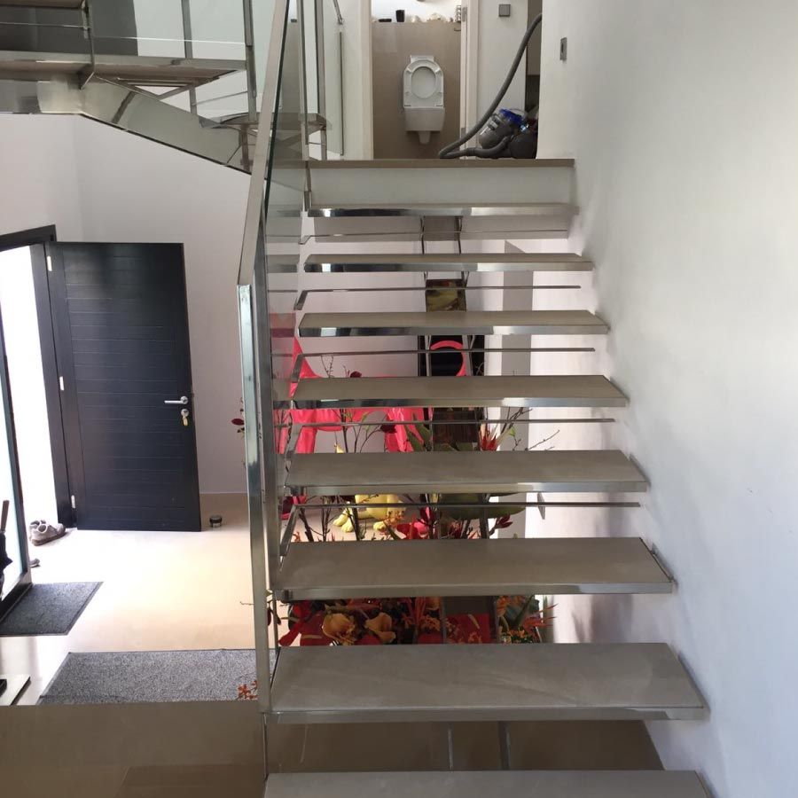 Una escalera con barandilla de vidrio que conduce al segundo piso.