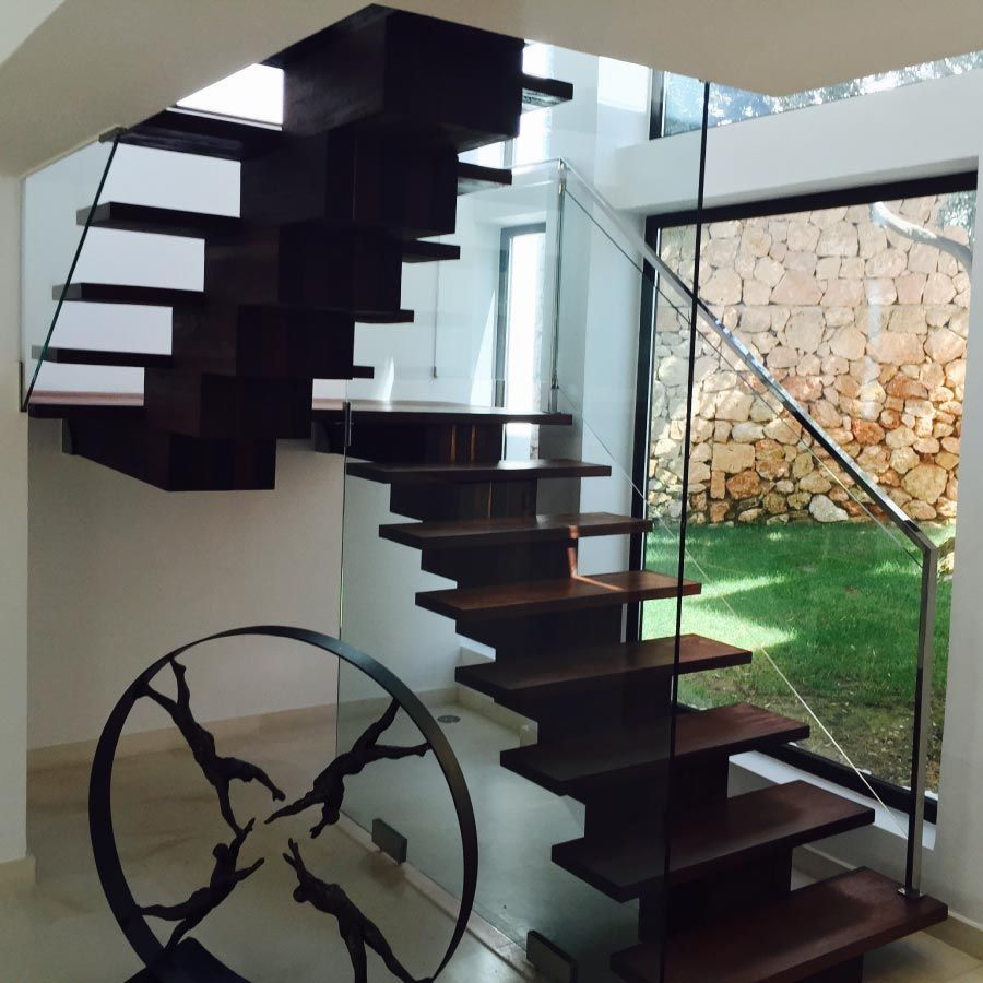 Una escalera con barandilla de cristal y una escultura delante de ella.