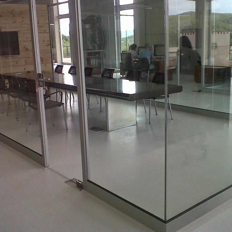 Una habitación con una mesa y sillas detrás de puertas de vidrio.