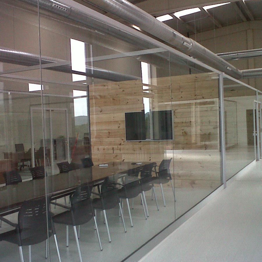 Una sala de conferencias con una mesa y sillas detrás de paredes de vidrio.