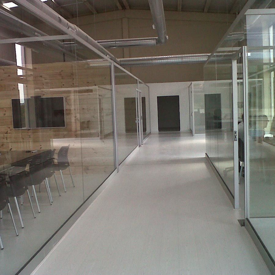 Un largo pasillo con paredes de cristal y sillas.