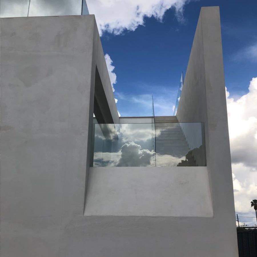Un edificio blanco con un balcón y un cielo azul al fondo.