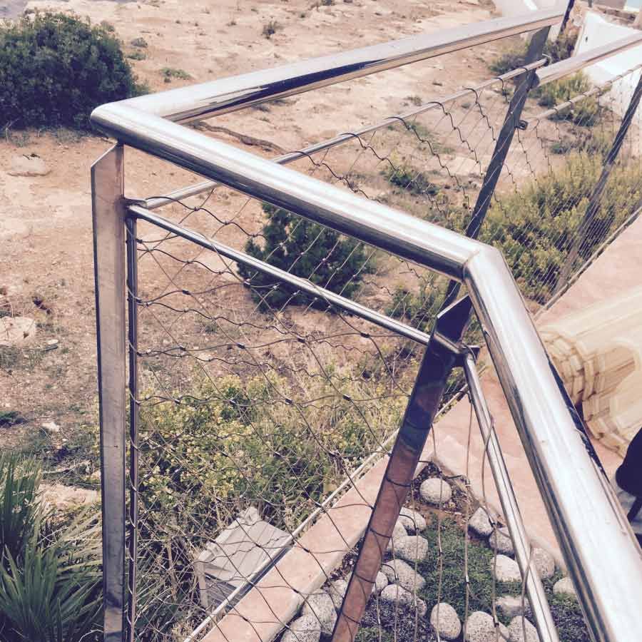 Una barandilla de acero inoxidable está rodeada de rocas y césped.