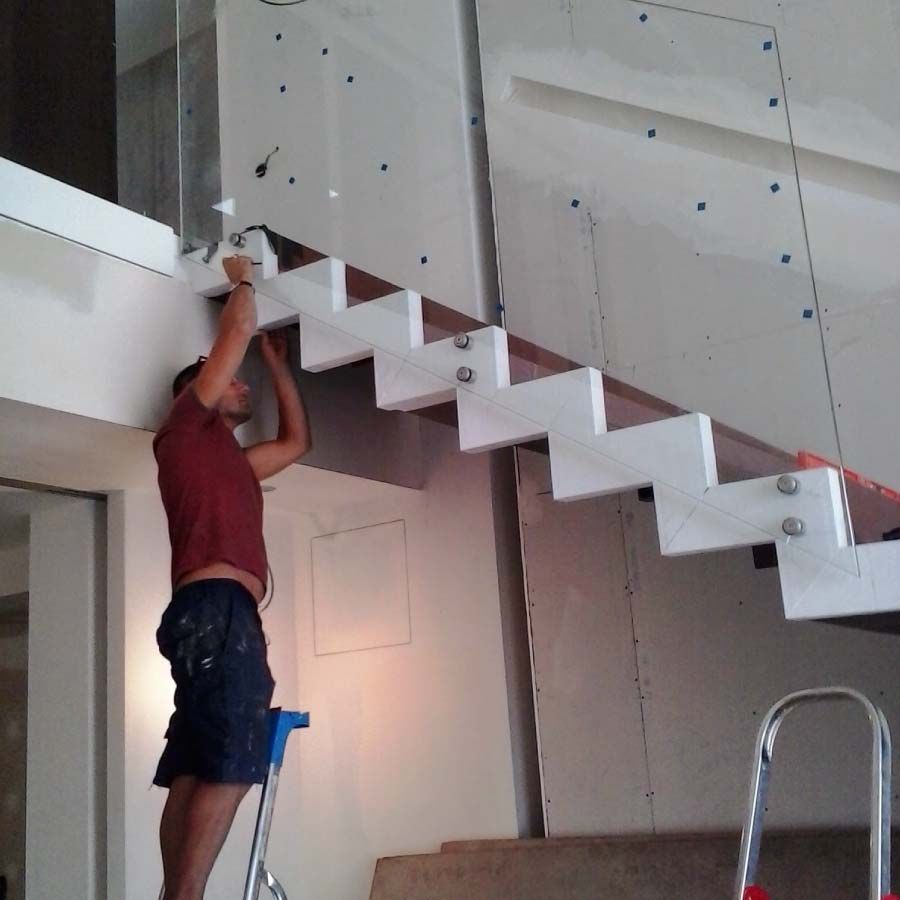 Un hombre está de pie en una escalera trabajando en una escalera.