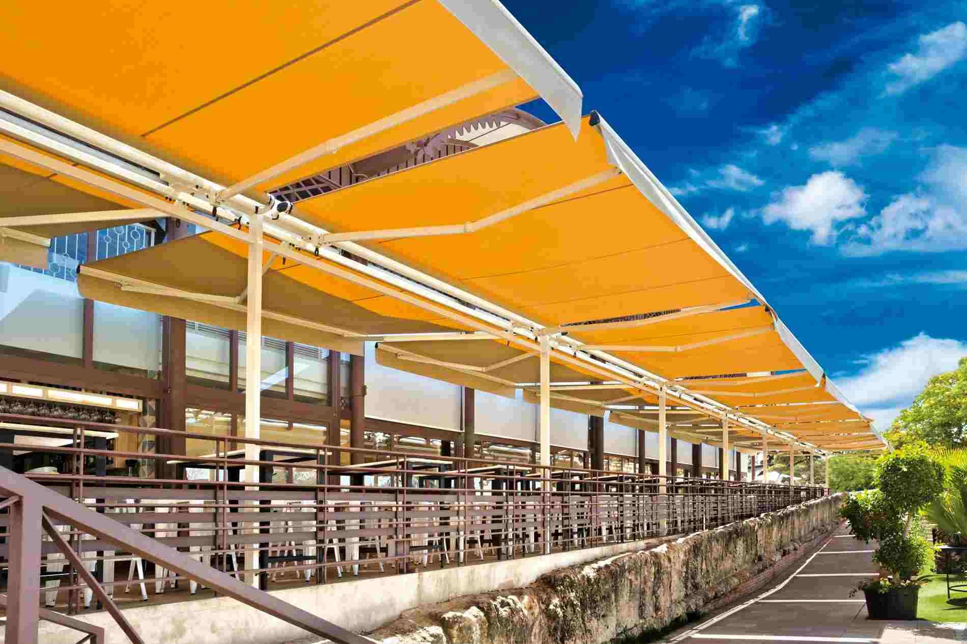 Un restaurante con un gran toldo amarillo sobre las mesas y sillas.